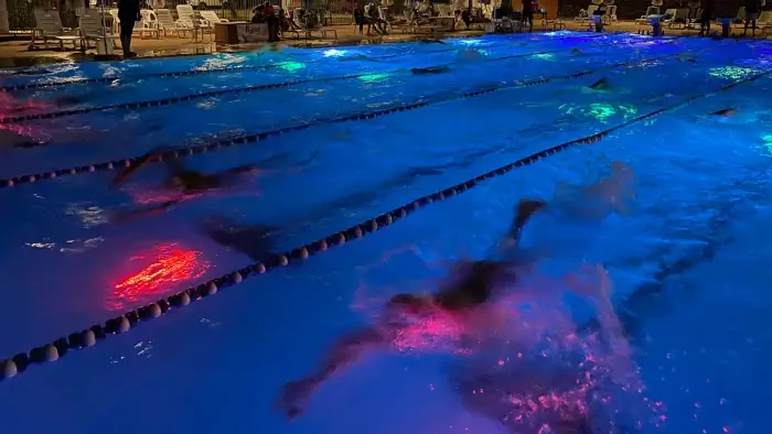 Ragazzi che nuotano di notte in piscina con l'ausilio del Virtual Swim Trainer